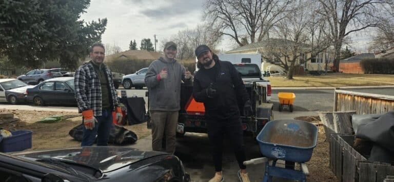 three white young adult males posing for a photo in front of a trailer while doing yard work