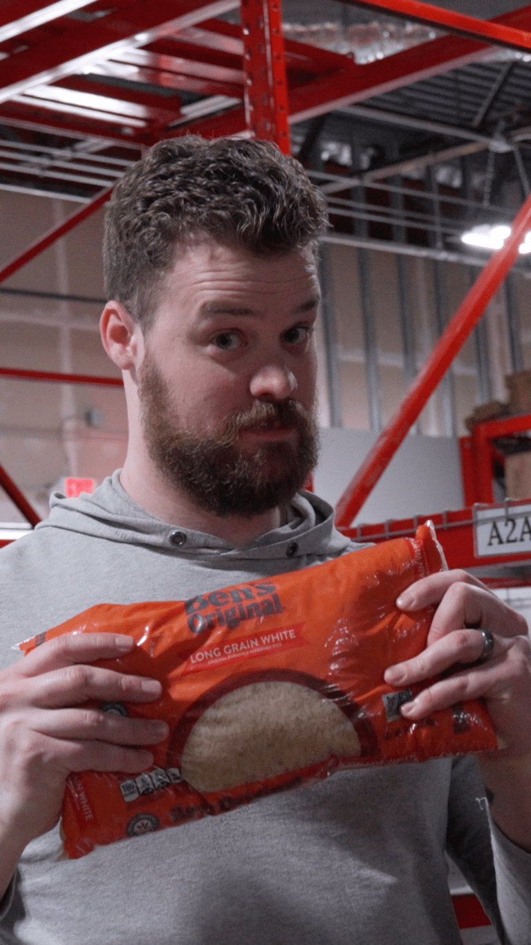 white young adult male looking at the camera while holding a bag of white rice