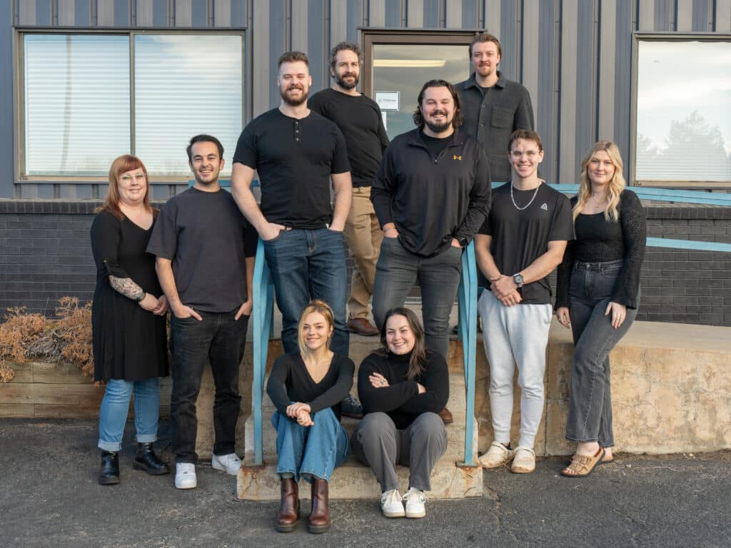 group of ten people standing outside on steps all wearing black t shirts and smiling at the camera